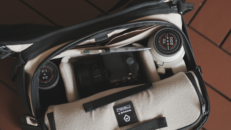 Open camera bag with Canon RF lenses and accessories on neutral fabric lining.