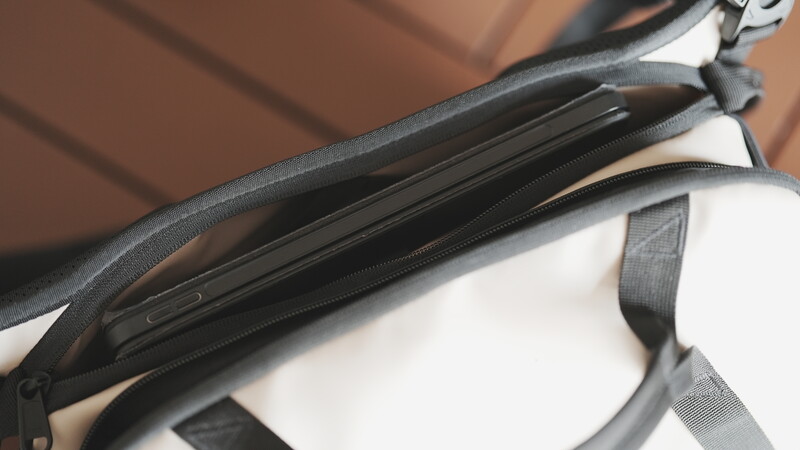 Close-up of camera bag zipper and strap details with white and black fabric visible.