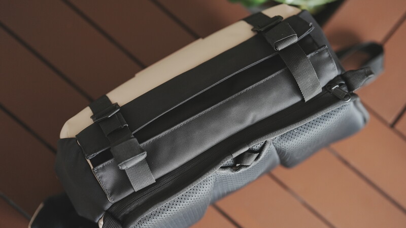Close-up of a camera shoulder strap attachment system with black plastic quick-release mounts and gray fabric webbing.