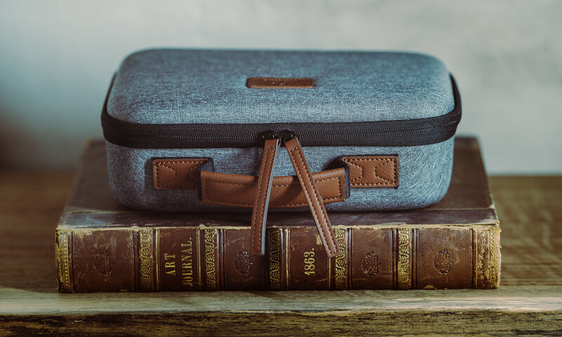 Vintage suitcase stacked on antique leather-bound books on a wooden surface.