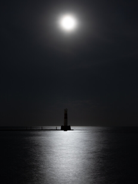 Photograph of a beacon light silhouetted against moonlit