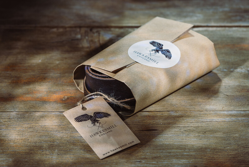 Kraft paper packaging with raven logo and hang tag on rustic wood surface.