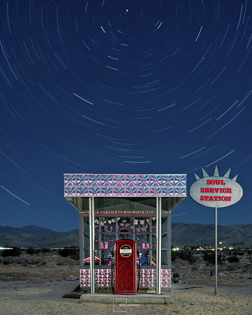Vintage gas pump station in desert landscape with star trail photography overhead.