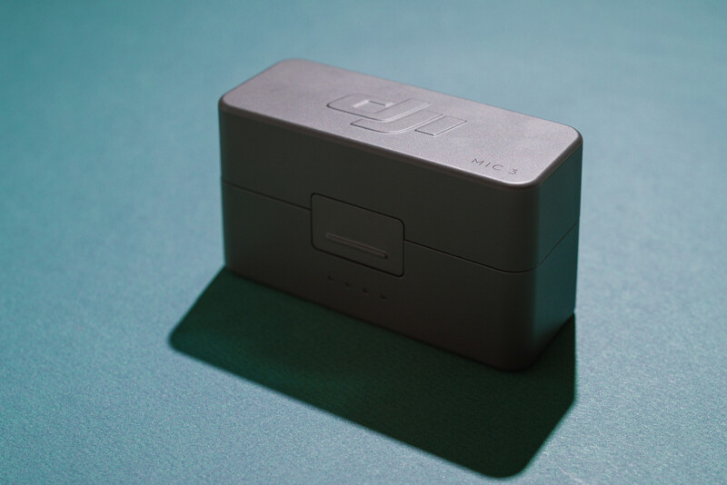 Black rectangular device with rounded edges and control buttons on a teal background.