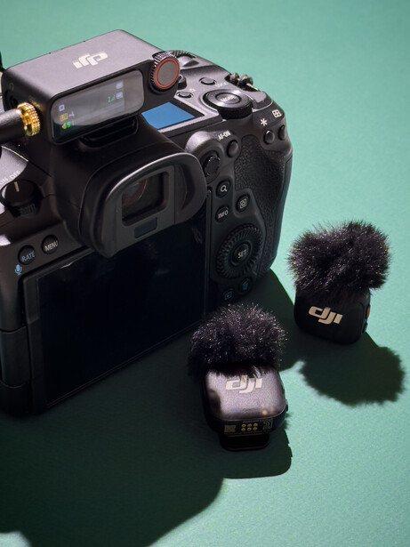 Professional camera with wireless microphone system mounted on top against turquoise background.