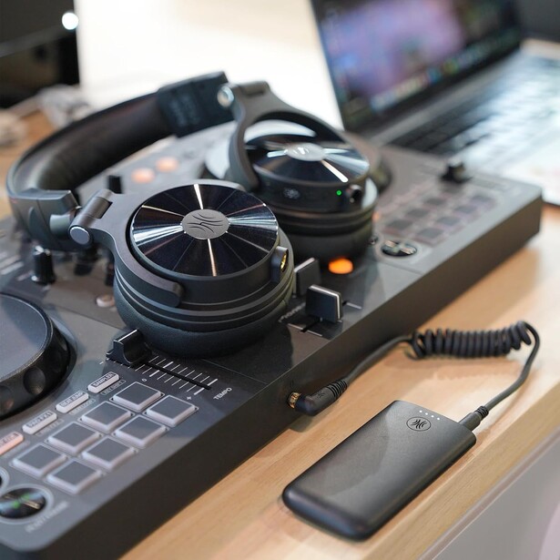 Professional audio equipment and headphones arranged on a laptop keyboard in a studio workspace.