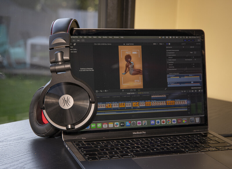 Professional over-ear headphones positioned on a laptop displaying video editing software with a portrait image in the timeline.