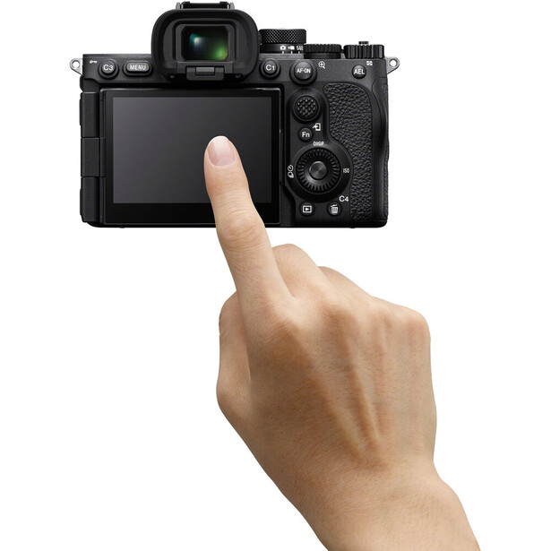 Hand pointing at the rear LCD screen of a mirrorless camera body shown from the back.