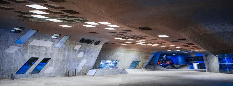 Modern concrete subway station with blue accent lighting and geometric architectural elements.