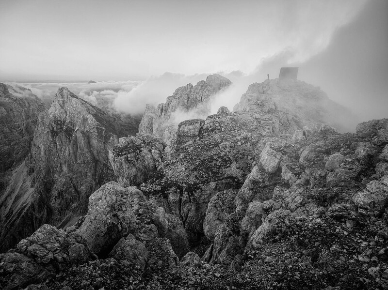 Misty mountain landscape with dramatic rock formations and a distant castle structure shrouded in fog.