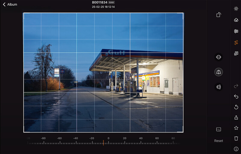 Gas station at dusk with illuminated canopy and grid overlay in editing interface.