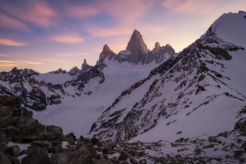 Snow-covered mountain peaks at dawn with jagged granite spires rising above an alpine glacier.