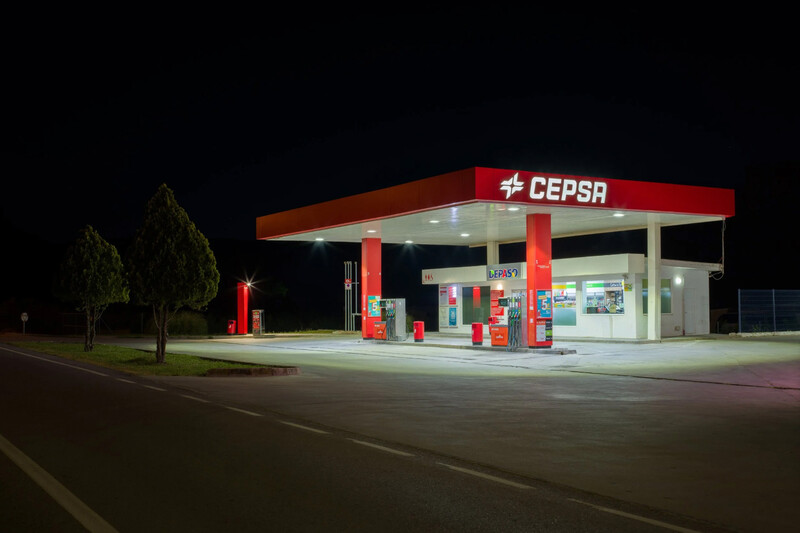 Nighttime photograph of a brightly lit gas station with red and white signage and overhead canopy.