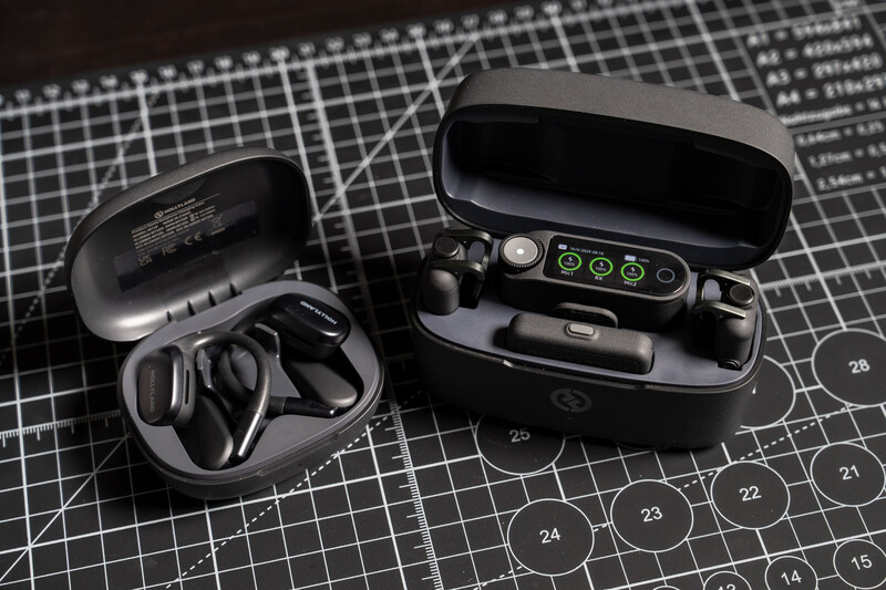 Two open black earbuds cases displaying wireless earbuds and charging accessories on a gridded technical diagram background.