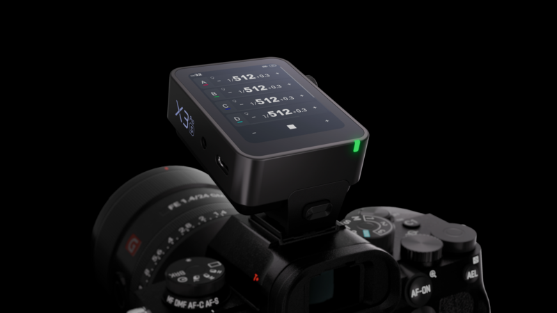 Wireless flash trigger mounted on DSLR camera with digital display screen showing channel settings.
