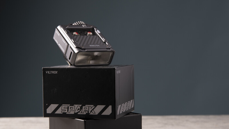 Viltrox Spark camera flash unit mounted on its packaging box against a neutral gray backdrop.