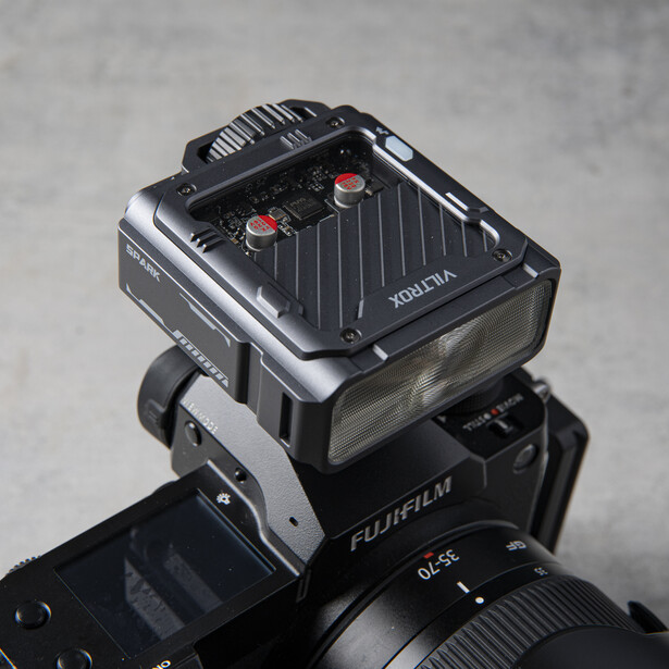Fujifilm camera with external flash unit mounted on top shoe.