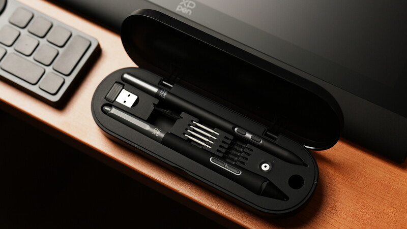 Open black cable organizer case displaying USB cables and accessories on a wooden desk next to a keyboard.