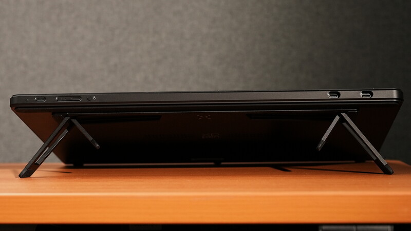 Black tablet computer propped up on collapsible metal stand against wooden surface.