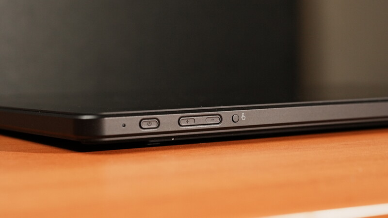 Close-up of a tablet's side edge showing power button and volume controls against an orange surface.