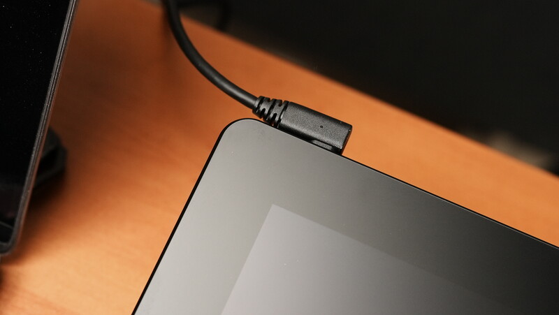 Power cable connected to a laptop computer positioned on an orange and black surface.