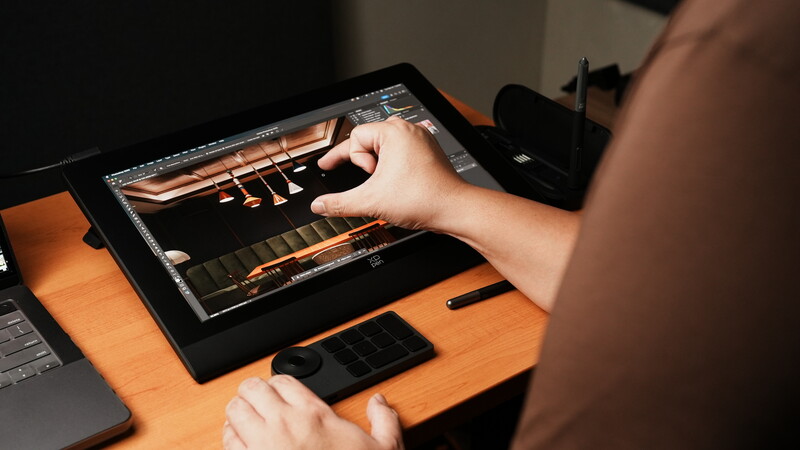 Photographer editing a piano performance image on a tablet using a stylus at a wooden desk.