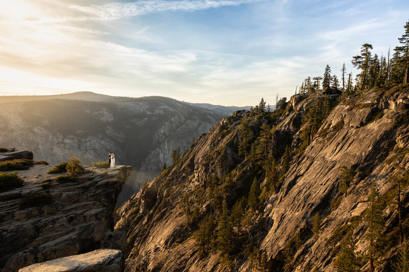 Steep forested mountainside with granite cliffs overlooking a valley at golden hour.