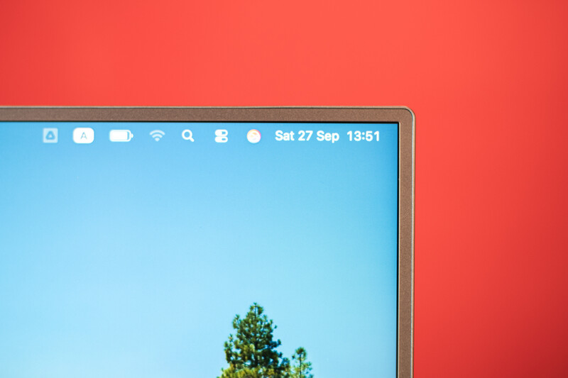 Screenshot of a desktop monitor displaying a minimal desktop with a tree against a blue sky, set against a red background.