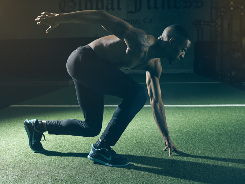 Athlete in a deep backbend stretch on artificial turf in dramatic side lighting.