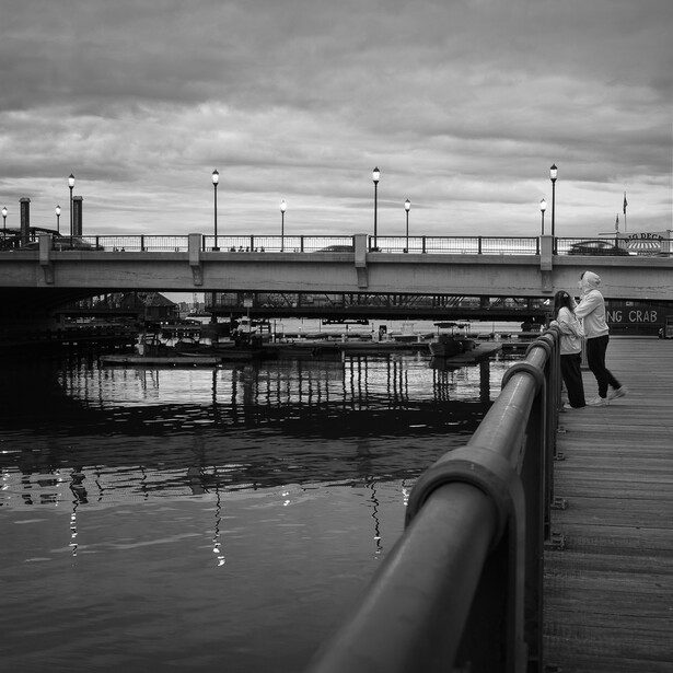 Photograph of a couple standing at a railing along a waterway