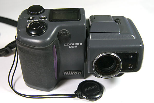 Two Nikon digital cameras displayed side by side with a lens cap and charging cable.