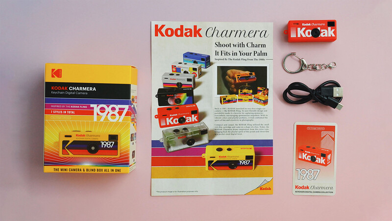 Vintage Kodak Charmera camera collection and marketing materials laid out on a pink surface.