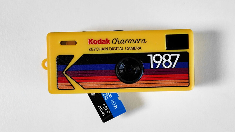 Kodak Charmera keychain digital camera from 1987 with yellow casing and colorful striped design.