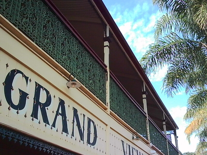 Weathered storefront with partial signage reading "GRAND" and climbing ivy against a cream and burgundy facade.