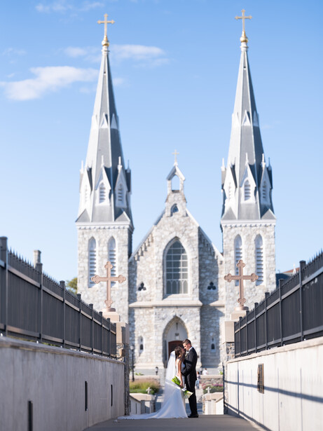 White neoclassical church with two tall spires and crosses, centered in frame with symmetrical approach.