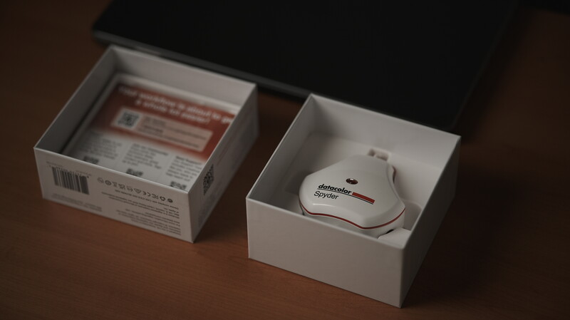 Two white product boxes on a wooden surface; left box displays red instruction text and barcode, right box contains a white ergonomic mouse.