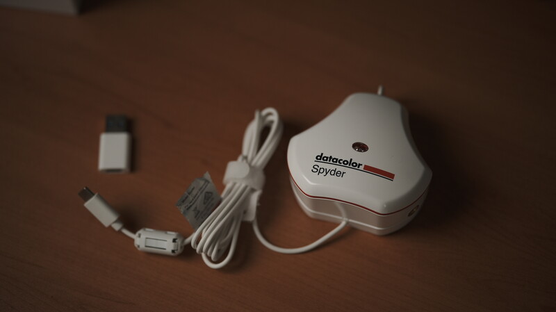 Datacolor Spyder color calibration device with cable and accessories on brown surface.