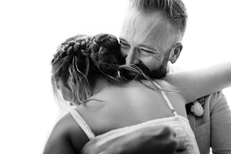 Man with beard embracing woman from behind in intimate black and white portrait.