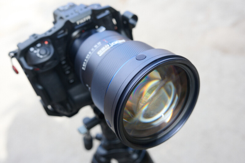 Professional mirrorless camera mounted on tripod with large telephoto lens attached.