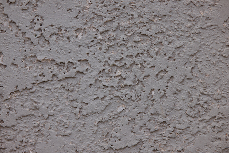 Close-up of rough concrete or stucco surface with varied texture and aggregate particles.