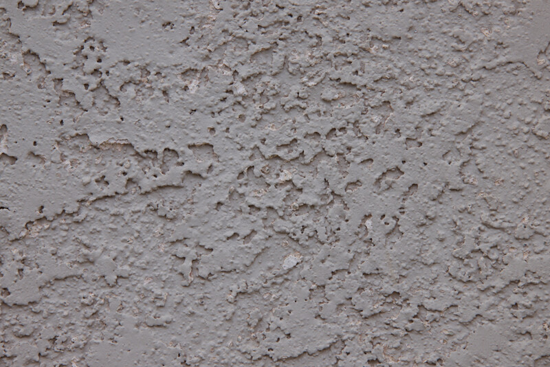 Close-up of rough, textured concrete or plaster surface with irregular peaks and valleys.