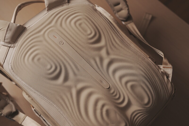 Cream-colored handbag with wavy textured surface and top handles, photographed from above with dramatic directional lighting.