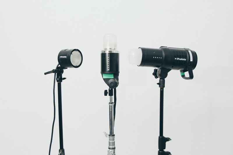 Three studio lighting fixtures mounted on stands against a white background.
