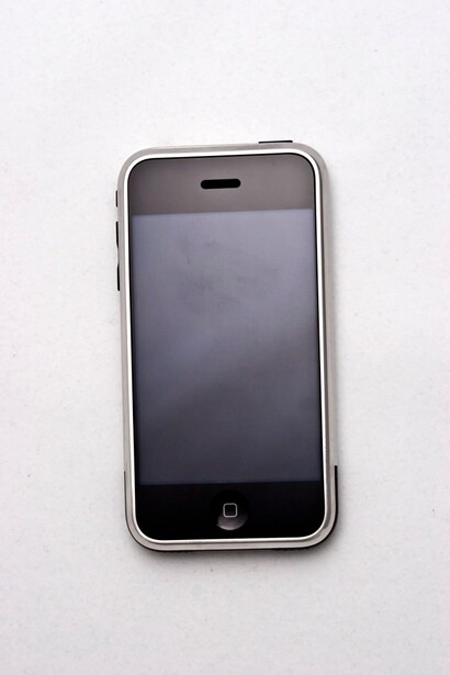 First-generation iPhone with silver bezel and black screen displayed on white background.