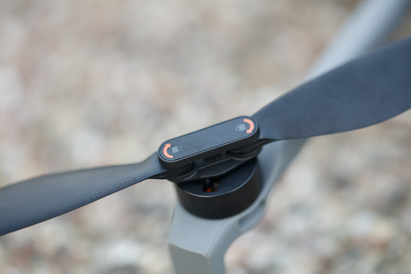 Close-up of a drone propeller arm connector and motor hub assembly against a blurred concrete background.