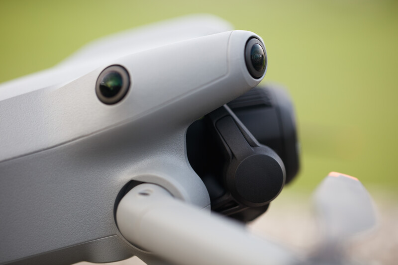 Close-up of a white drone showing dual cameras mounted on top and a black gimbal stabilizer below.