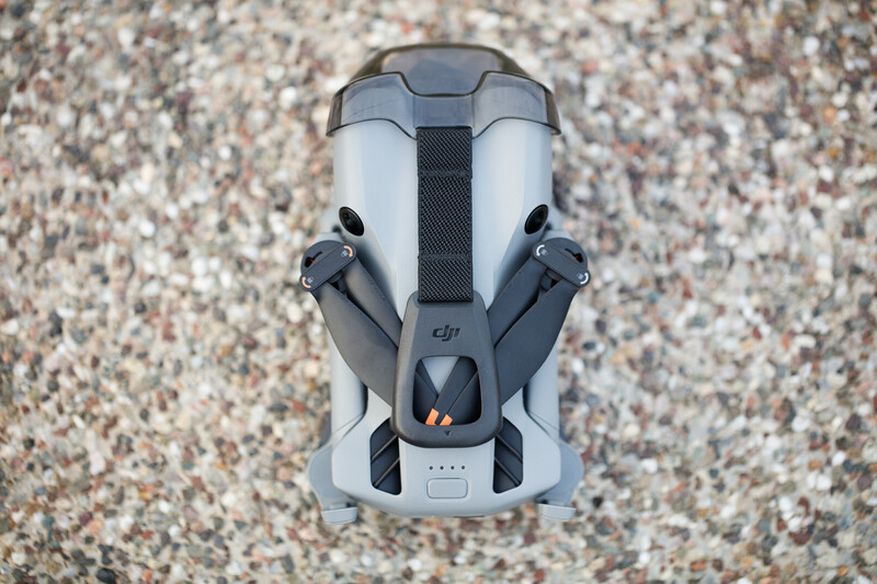 DJI drone photographed from above on a gravelly surface, showing folded arms and propellers.