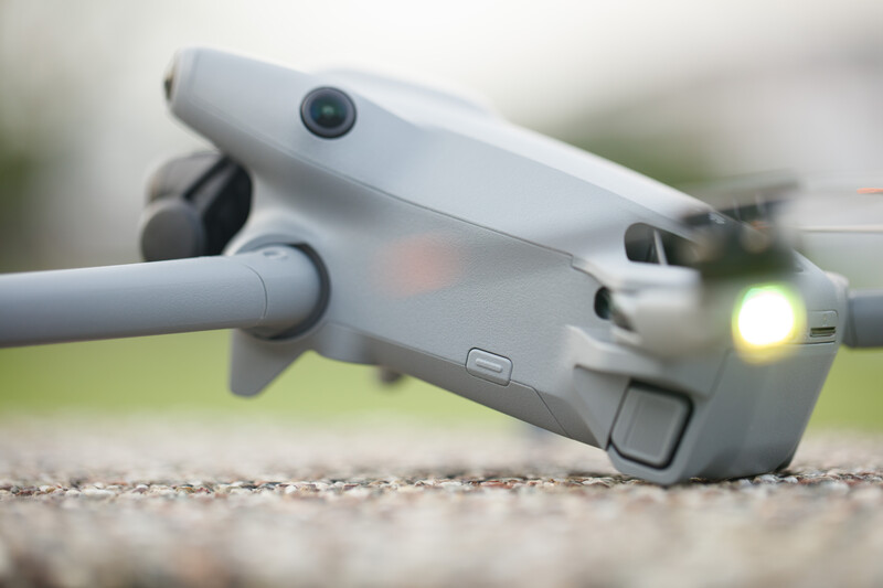 DJI Mavic Air 2 drone positioned on gravel with gimbal arm extended and LED light illuminated.