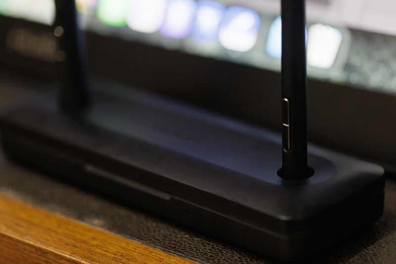 Close-up of a black wireless router with two antennas on a wooden surface.