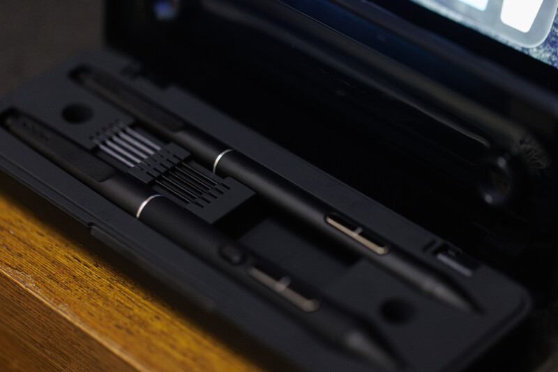 Two black brushes with metal ferrules resting on a dark surface next to camera equipment.